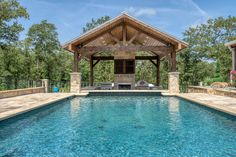 a pool with a gazebo next to it and an outdoor kitchen in the background