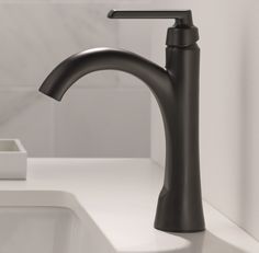 a black faucet sitting on top of a bathroom sink next to a white counter