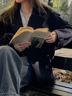 a woman sitting on a bench reading a book