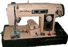 an old pink sewing machine sitting on top of a black stand with buttons and knobs