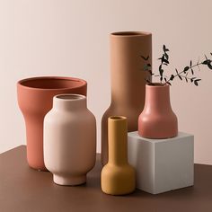 three different vases sitting on top of a table next to each other, one with a plant in it