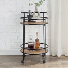 a black metal and wood serving cart with bottles on it next to a white brick wall