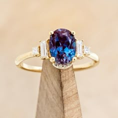 a blue and white ring sitting on top of a wooden block with three diamonds around it