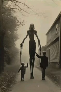 an old black and white photo of a woman walking with two children