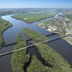 an aerial view of a river and city in the distance with trees on both sides