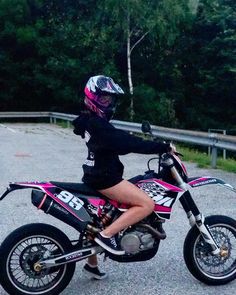 a woman sitting on top of a pink dirt bike