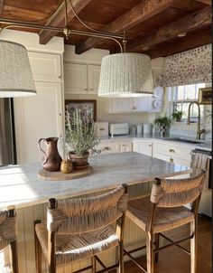 a kitchen island with three chairs and a potted plant sitting on top of it