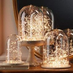 there are three glass domes with lights in them on the table next to a mirror