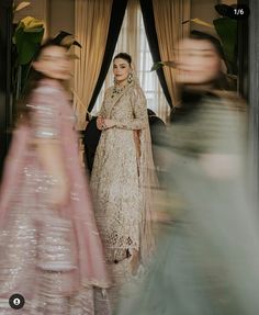 a woman standing in front of a mirror wearing a white and pink dress with long sleeves