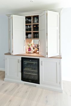 an open cabinet in the middle of a kitchen with wine bottles and other items on it