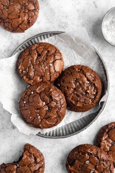 three chocolate cookies on a plate with one broken in half