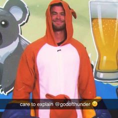 a man wearing an orange and white animal onesie standing in front of a beer advertisement