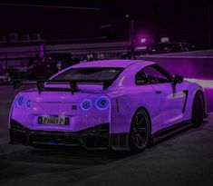 a purple sports car parked in a parking lot at night with lights on it's side