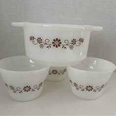 three white bowls with brown designs on them