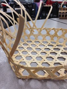 a wooden basket sitting on top of a table in a room filled with tables and chairs