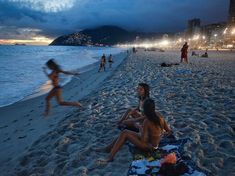 some people are sitting on the beach at night