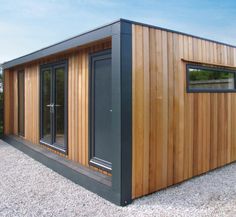 a small wooden building sitting in the middle of a gravel area next to some flowers