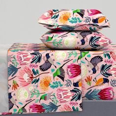 three pillows stacked on top of each other in front of a gray background with colorful flowers and leaves