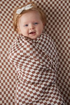 a baby is wearing a brown and white checkered blanket