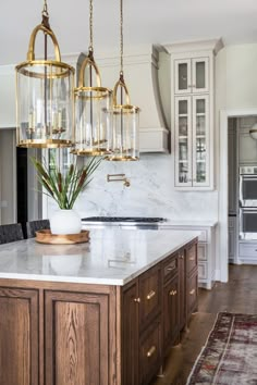 a kitchen with marble counter tops and gold accents on the lights hanging from the ceiling