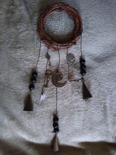 a wind chime with bells and beads hanging from it's side on a white blanket