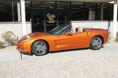 an orange sports car parked in front of a building