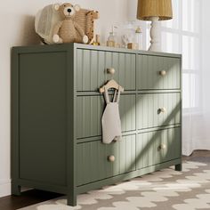 a green dresser with two teddy bears on top and one stuffed animal hanging from the drawer