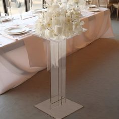 a tall clear vase filled with white flowers on top of a table