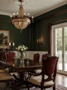 an elegant dining room with green walls and chandelier