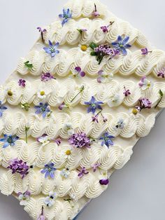 a cake with white frosting and purple flowers on it