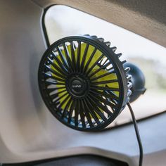 an electric fan is plugged in to the side of a car's dashboard