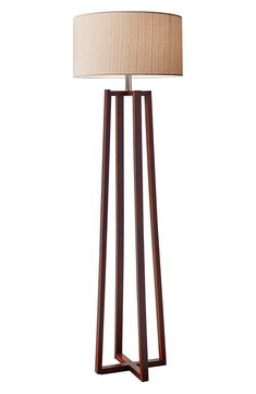 a wooden floor lamp with a beige shade on it's side and a white background