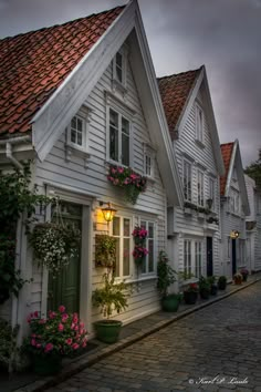 a row of white houses with flowers on the windows