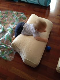 a toddler playing with a ball on the floor in front of a sleeping bag