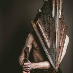 a shirtless man holding a large metal object