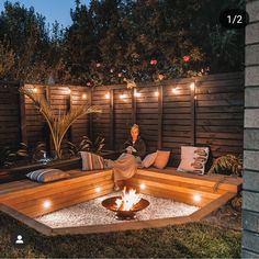 a woman sitting on a bench in the middle of a yard with lights strung around her