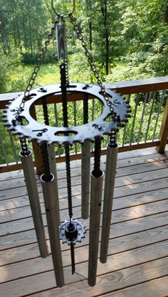 an outdoor wind chime on a deck with trees in the background