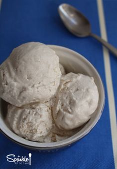 two scoops of ice cream in a bowl on a blue tablecloth with spoon