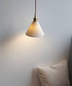 a white lamp hanging from the side of a wall next to a pillow on a bed