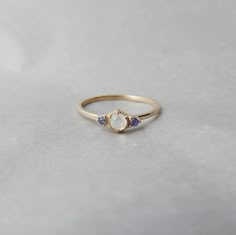 a gold ring with an opal and tan sapphire stones on the side, sitting on a white surface