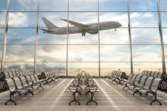 an airplane is flying in the sky over many empty chairs and benches at an airport