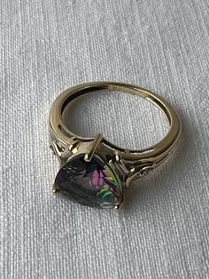 Lots of flash and colour in this lovely 14K yellow gold and trilliant cut mystic topaz ring.   Single diamonds on either side of the topaz offer a bit more subtle sparkle.  The only mark on the band is an R in a circle.  Both diamonds and topaz tested on my gem tester, the gold has been jeweller tested as 14K.  On my mandrel the ring fits to size approx. 6.5 (halfway between 6 1/2 - 6 3/4)  I try to provide as much information as possible about the size of a ring but if more measurements are nee Gold Topaz Multi-stone Ring, Elegant 14k Gold Multi-stone Topaz Ring, 14k Gold Multi-stone Topaz Ring, Mystic Topaz Earrings, Mystic Topaz Ring, Mystic Topaz, Ring Fit, Topaz Ring, Ring Box