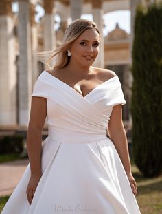 a woman in a white wedding dress posing for the camera with her hand on her hip