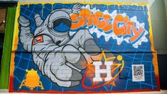 a mural on the side of a building that says space city with an elephant holding a rocket