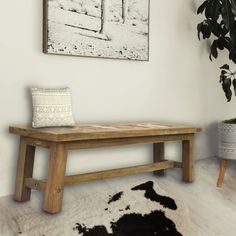 a wooden bench sitting on top of a white floor next to a potted plant