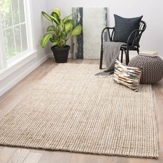 a living room with a chair, rug and potted plant