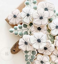 cookies decorated with white and blue flowers are on a wooden board next to a spoon