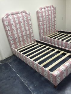 two pink and white beds with matching headboards in an empty room on concrete flooring