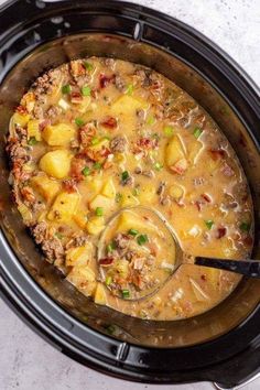 a crock pot filled with soup and potatoes