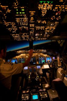 a man is sitting in the cockpit of an airplane at night with many lights on